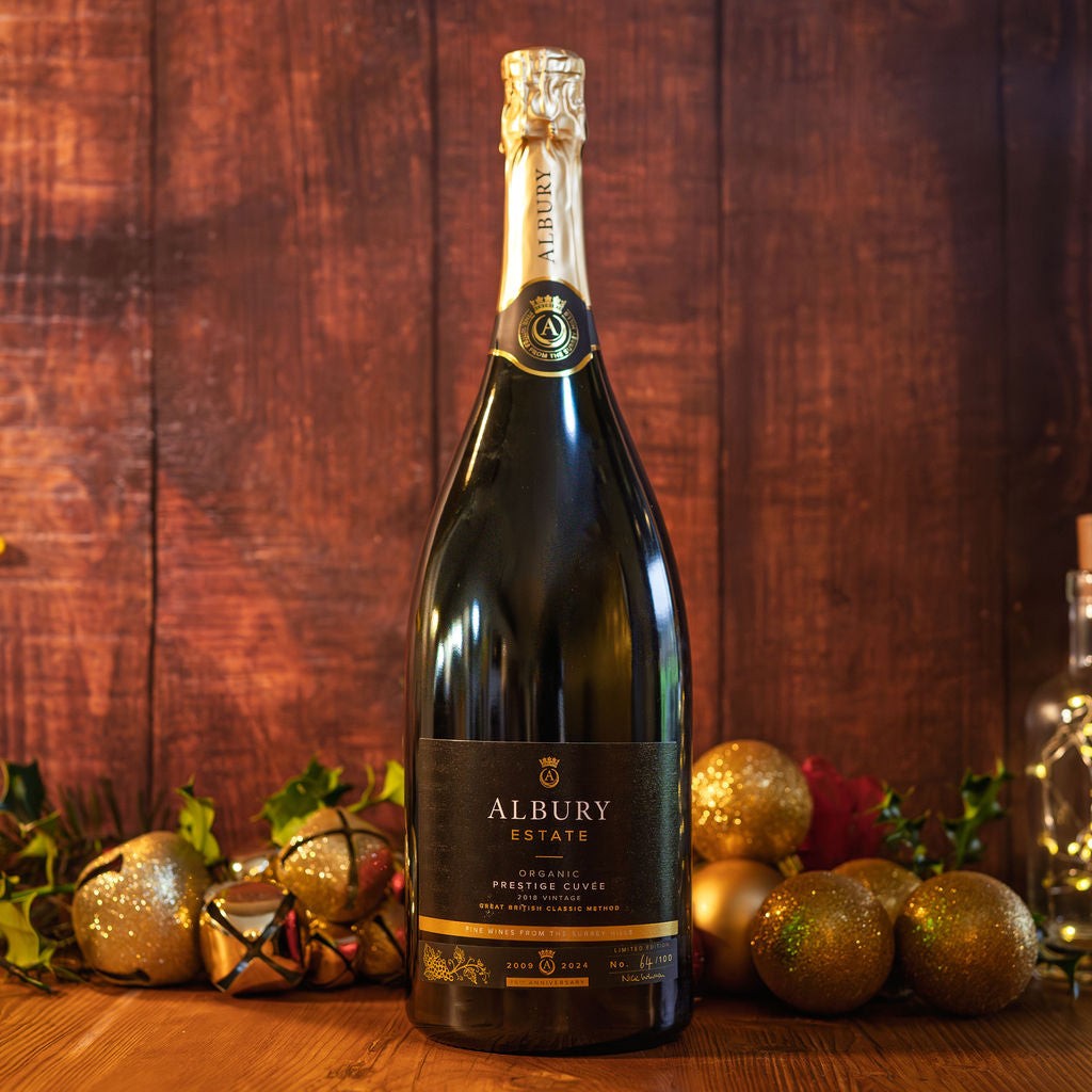 Bottle of Albury Estate champagne on a wooden surface with festive decorations.