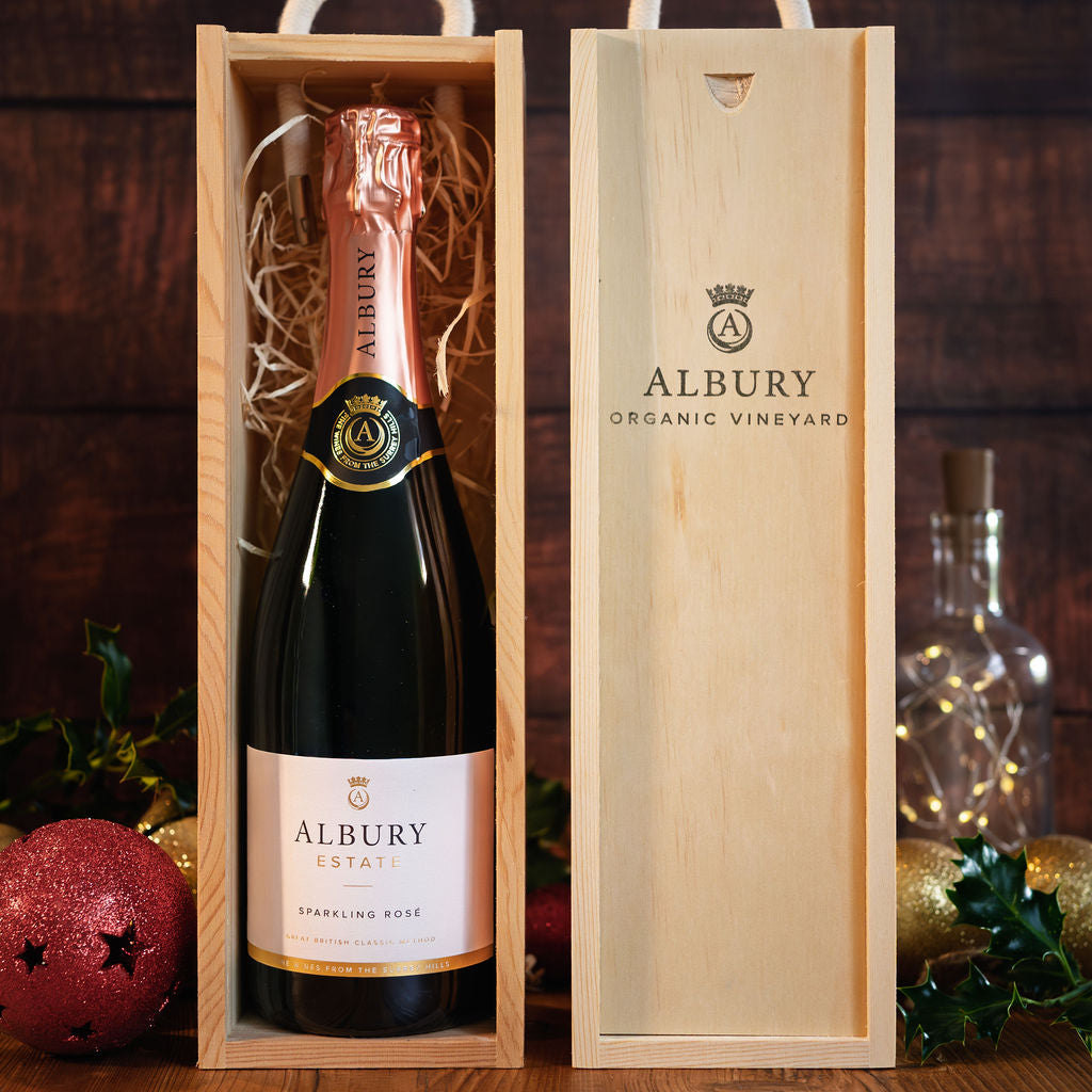 Bottle of Albury sparkling rose wine in a wooden gift box with festive decorations in the background.